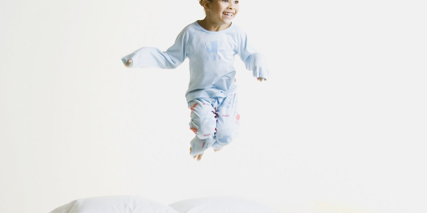 African girl jumping on bed
